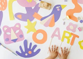 Creative art and craft layout with colorful paper cutouts and child’s hands, viewed from above.